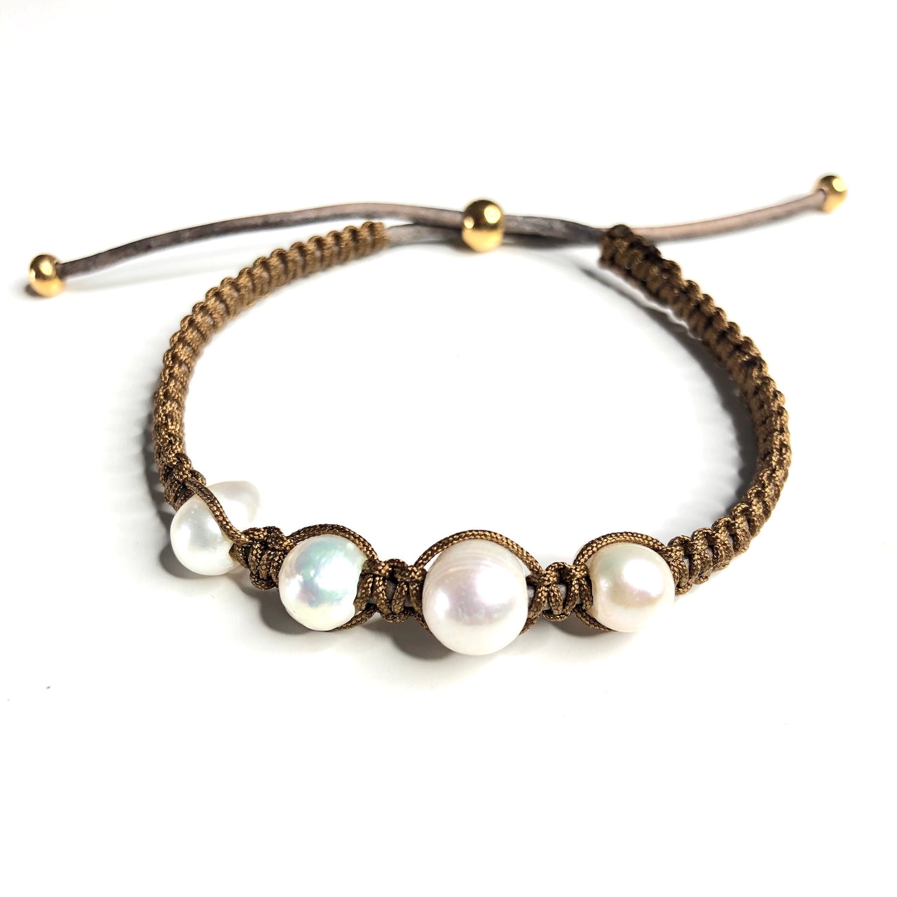 Pulsera cuero natural con macramé marrón dorado y perlas cultivadas. Esta preciosa pulsera tiene detalles de Zamak en baño de oro y es ajustable.