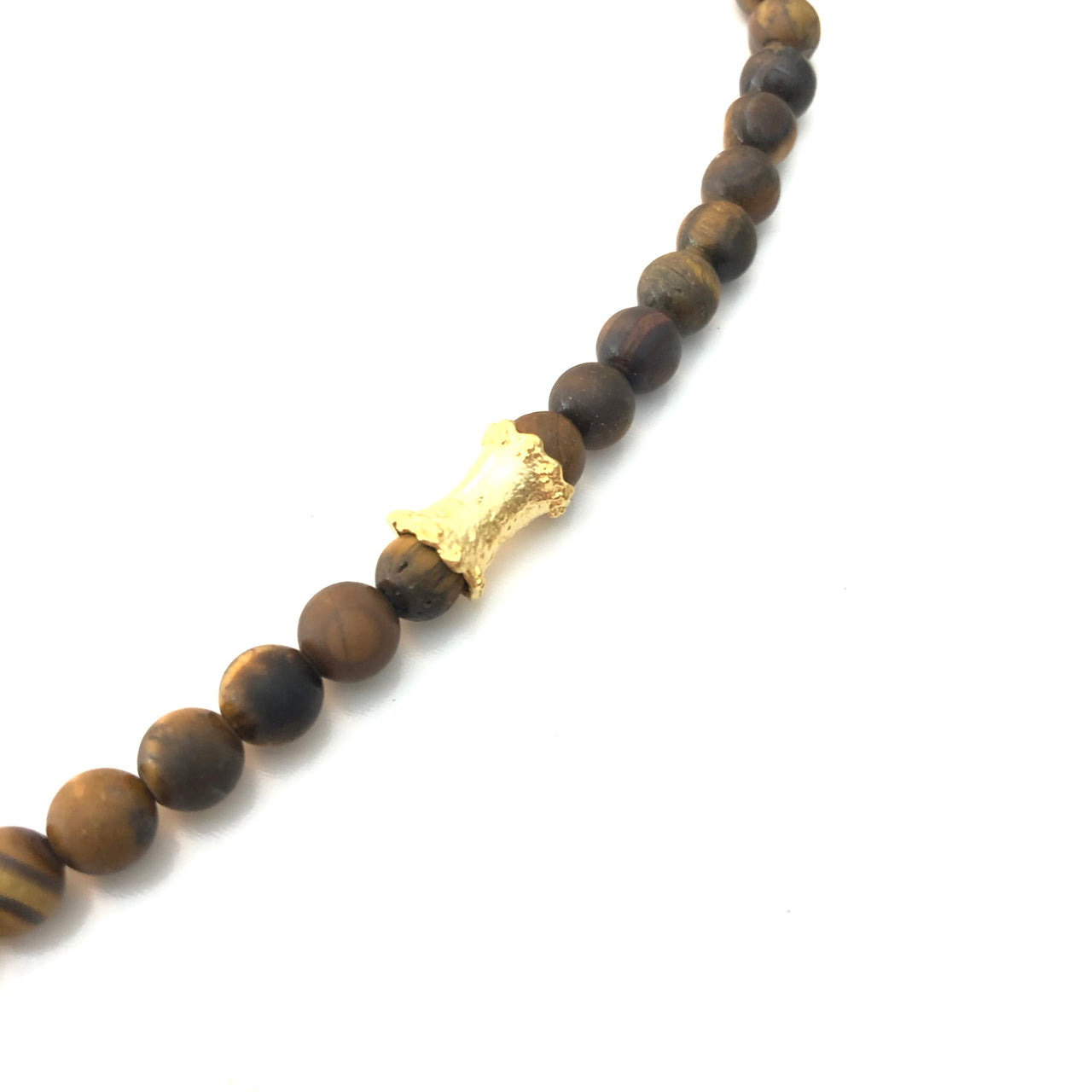 Imponente collar corto de ojo de tigre natural con tubo martillado y con un espectacular hoja de Zamak con baño de oro mate. Esta pieza te quedará estupenda con tu prenda favorita. Detalle tubo