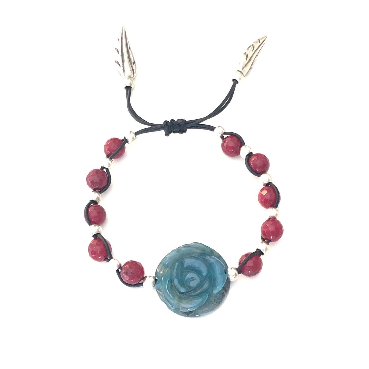 Elegante pulsera ajustable de ágata facetada borgoña entrelazadas con las de zamak con baño de plata. El centro de atención de la pieza es la espectacular rosa de ágata turquesa que junto con los terminales de pluma de Zamak con baño de plata permiten combinarla con tus prendas de diario. Desde arriba